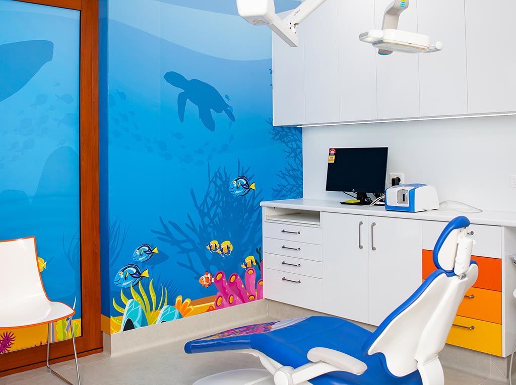 Child-friendly paediatric dental treatment room with ocean-themed wall mural at NLPD