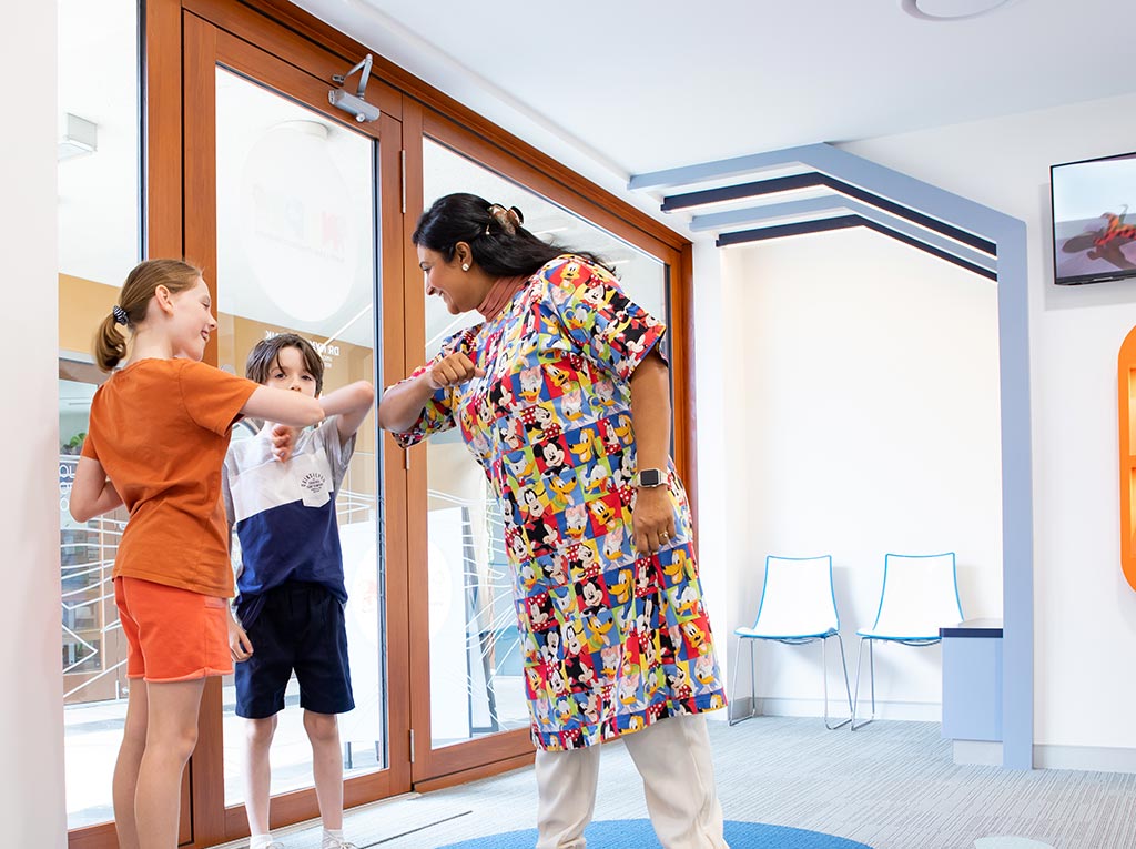 Children greeting an NLPD team member with elbow bumps at the clinic entrance