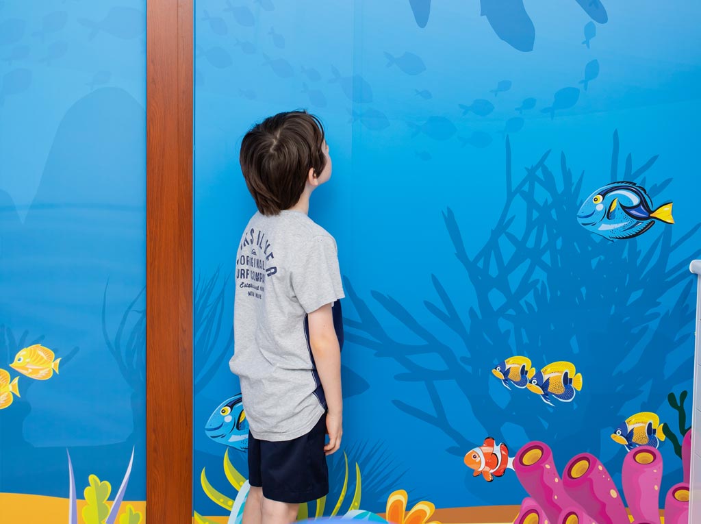 Young patient admiring the underwater mural wall at North Lakes Paediatric Dentistry